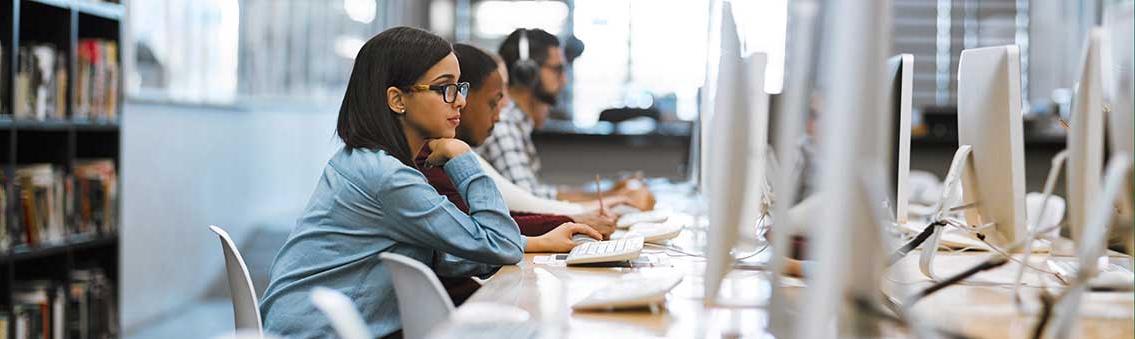 group of graduate degree students working on computers in the library at campus